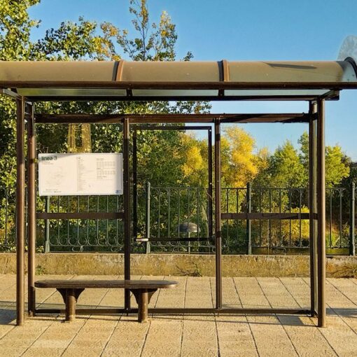 An empty bus shelter beside trees on a sunny day