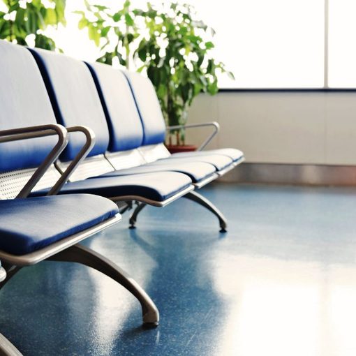 Rows of empty blue waiting-room chairs beside a bright window