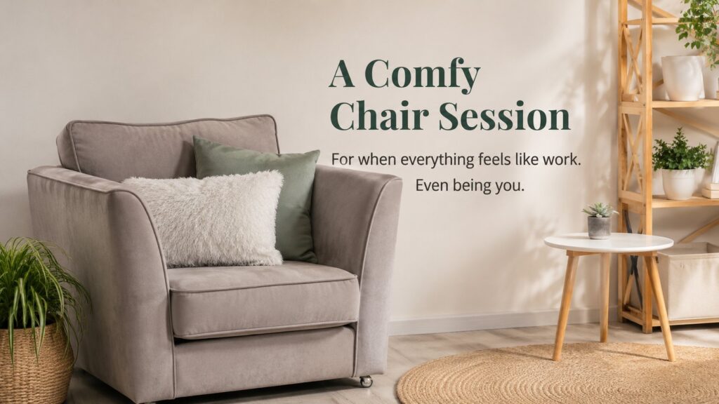A cosy taupe armchair with a fluffy white cushion and a sage green cushion, beside a small round table with a succulent and a wooden plant shelf, in a warm, softly lit room. Text on the image reads: "A Comfy Chair Session — For when everything feels like work. Even being you."